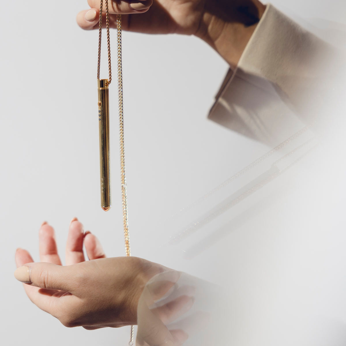 Der EASE Anhänger hängt an der Kette über einer offenen Hand