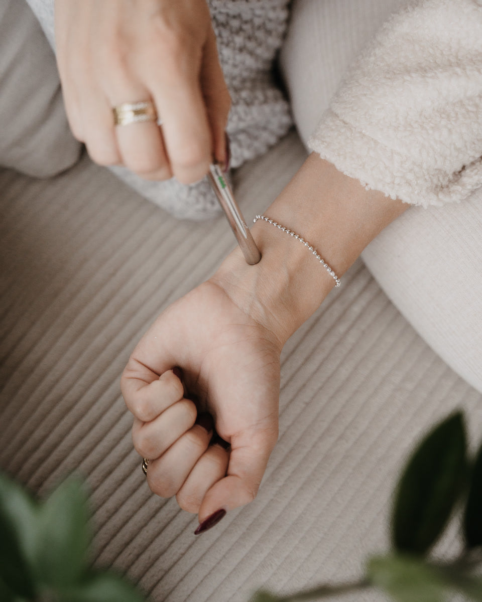 Der EASE Anhänger in der Hand, die Spitze drückt auf den Handrücken