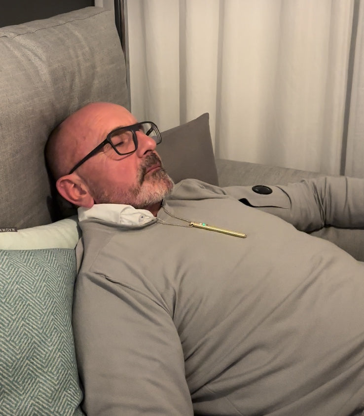 Kunde liegt mit geschlossenen Augen auf dem Sofa und trägt EASE in Gold