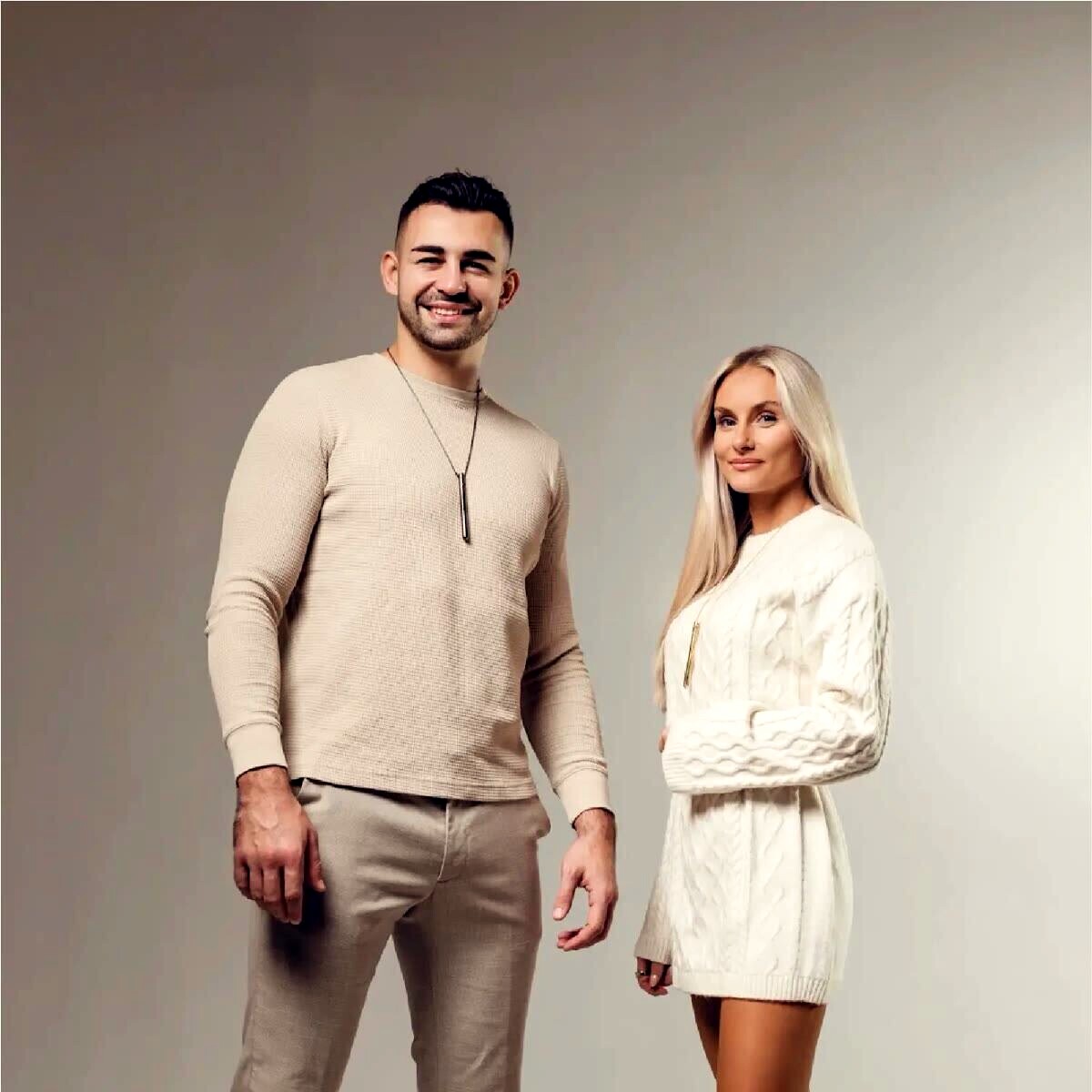 Ein Mann und eine Frau tragen die EASE Kette über dem Pullover
