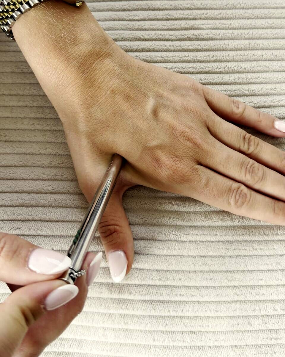 Der EASE Anhänger in der Hand, die Spitze drückt auf den Handrücken